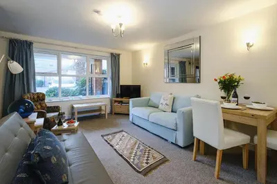 a living room with a blue couch and a table at 1 Coastguard Court in Aldeburgh