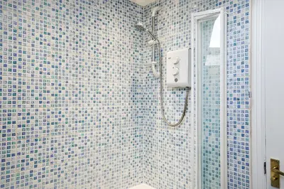a bathroom with a shower with blue tiles at Victoria Gardens in Colchester