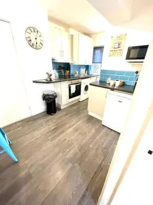 a kitchen with a wooden floor and a clock on the wall at Serene and Cozy 1-Bedroom House with Parking in Cambridge