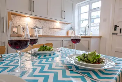 a table with two plates of food and wine glasses at Pelican Cottage, Aldeburgh in Aldeburgh