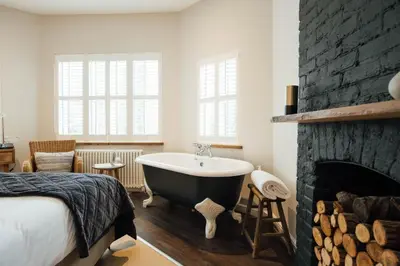 a bedroom with a bath tub next to a fireplace at The Fox at Willian in Letchworth