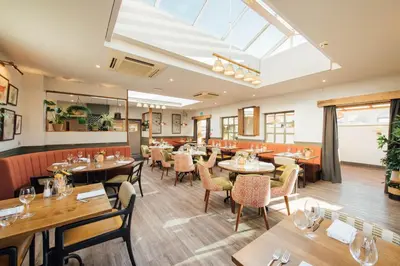 a restaurant with tables and chairs and a skylight at The Fox at Willian in Letchworth