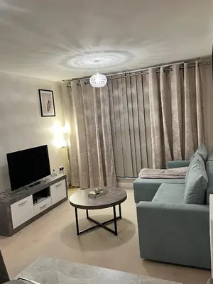 a living room with a couch and a tv and a table at Next-Stop Haven in Harlow