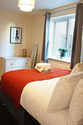 a bedroom with a bed with a red blanket and a window at Host & Stay - Clacton Coastal Hideaway in Clacton-on-Sea