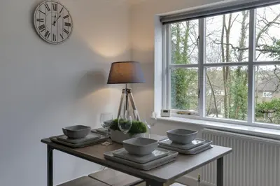 a table with glasses and a lamp and a clock on a wall at Entire home/flat perfect for contractors in Bishops Stortford
