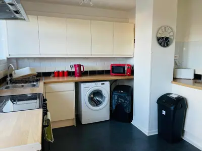 a kitchen with a washing machine and a microwave at St Ives, King Bed Cosy home, parking, fast Wi Fi in St Ives