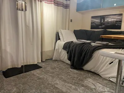 a bedroom with a bed and a table and curtains at Studio Annex in Cottenham