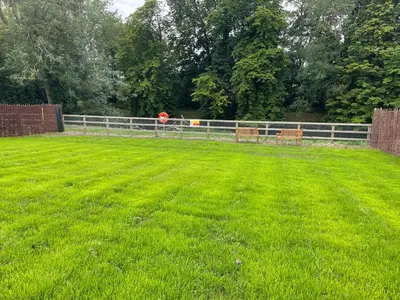 a grassy field with two benches in front of a fence at Wimbish Hall Cabins in Wimbish