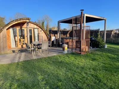 a gazebo with a table and chairs in a yard at Wimbish Hall Cabins in Wimbish
