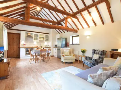 a living room with a table and chairs and a kitchen at The Stables in Colchester