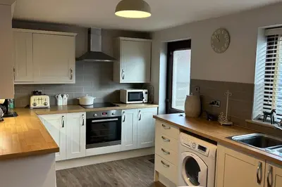 a kitchen with white cabinets and a stove top oven at Cosy 2 bed, home from home in Haddenham
