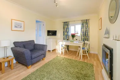 a living room with a blue couch and a table at The Quarter Deck in Aldeburgh