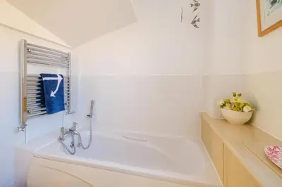 a white bathroom with a tub and a vase of flowers at The Quarter Deck in Aldeburgh