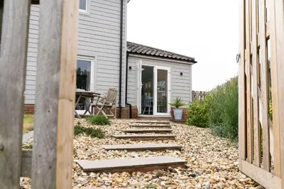 a backyard with a stone walkway leading to a house at The Garden Flat in Aldeburgh