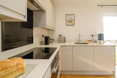 a white kitchen with white cabinets and a sink at Three Tuns - Garden Suite 1 in Wickham Market
