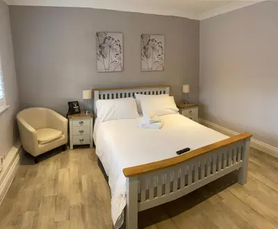 a bedroom with a large white bed and a chair at Ye Olde Plough House in East Horndon