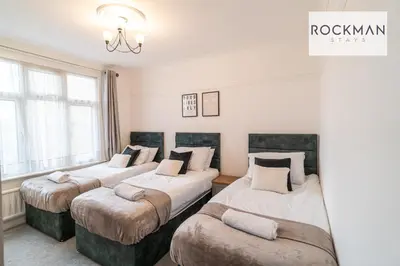 a room with three beds and a chandelier at 5 Bed Apartment Close To Beach with Off-street parking - Perfect for Contractors - Fast Wi-Fi - Close to beach in Southend-on-Sea
