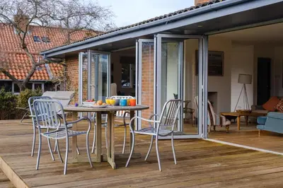 a patio with a table and chairs on a deck at Lowlands in Thorpeness