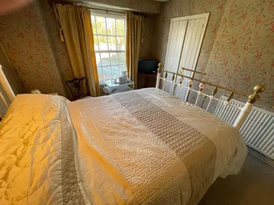 a bedroom with a large white bed with a window at The Bridge Street Historic Guest House in Sudbury