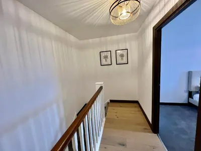 a hallway with a staircase and a chandelier at Walnut Tree Penthouse Next to Train Station in Cambridge