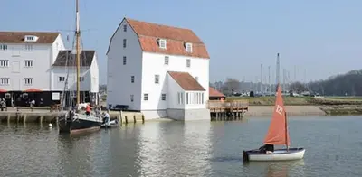 a small sail boat in the water next to a building at SkyFall in Grundisburgh