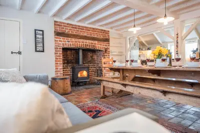 a living room with a brick fireplace and a table at Ivy House, Mells in Halesworth