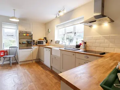 a kitchen with white cabinets and a wooden floor at The Brambles in Colchester