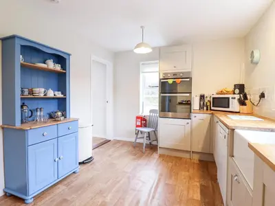 a kitchen with blue cabinets and wooden floors at The Brambles in Colchester