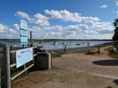 a sign in front of a body of water with boats at Rockhopper Cottage, Waldringfield in Woodbridge