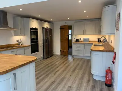 a large kitchen with white cabinets and wooden floors at Rockhopper Cottage, Waldringfield in Woodbridge
