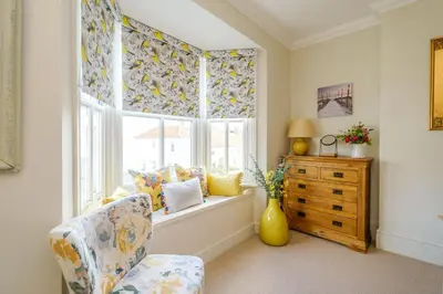 a living room with a chair and a window at Shearwater Cottage in Aldeburgh