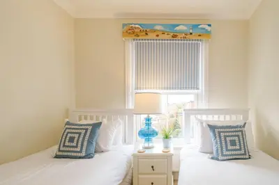 two twin beds in a bedroom with a window at Shearwater Cottage in Aldeburgh