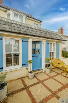 a house with blue doors and a patio at Shearwater Cottage in Aldeburgh