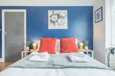 a blue bedroom with a large bed with red pillows at The Modern Cambridge Studio 4 in Cambridge