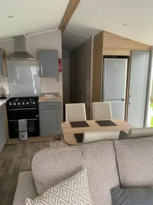 a kitchen with a couch and a table in a room at Kellysholidayhomes NEW Malton 3 bedroom Caravan in Weeley