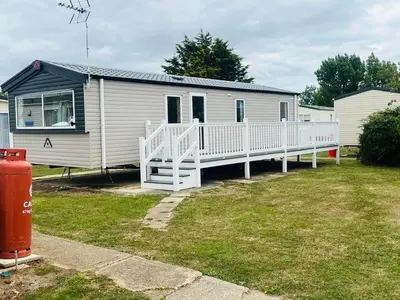 a white mobile home with a porch and a yard at Serenity Holiday Home in Saint Osyth