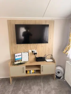 a flat screen tv on top of a wooden entertainment center at Serenity Holiday Home in Saint Osyth
