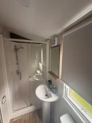a white bathroom with a sink and a shower at Serenity Holiday Home in Saint Osyth
