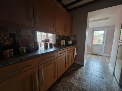 a kitchen with wooden cabinets and a tile floor at Primroses, Wood Farm in Shipdham