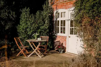 a table and chairs sitting in front of a door at Butley Priory Cottage in Woodbridge