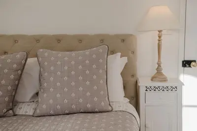 a bed with a pillow and a lamp on a table at Butley Priory Cottage in Woodbridge