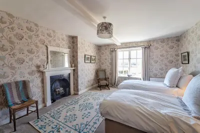 a bedroom with two beds and a fireplace at Butley Priory Farmhouse in Woodbridge