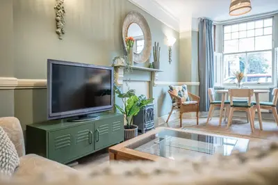 a living room with a flat screen tv on a green cabinet at Villa Verde in Aldeburgh