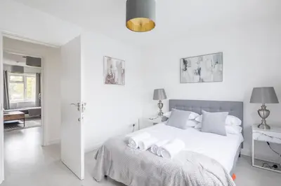 a white bedroom with a bed and a desk at Lovely 2 bedroom apartment - ideal location in Cambridge