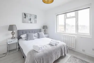 a white bedroom with a bed with towels on it at Lovely 2 bedroom apartment - ideal location in Cambridge