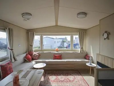a living room with a large white couch and windows at Lighthouse Holiday Retreat in West Mersea