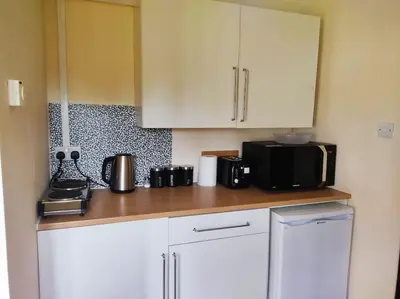 a kitchen with white cabinets and a black microwave at The Retreat in Tibenham