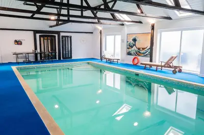 a swimming pool with blue water in a building at Amazing Spa Country House with Indoor Pool, Sauna and Steam Room in Tibenham