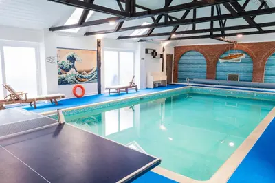 a large swimming pool with blue water at Amazing Spa Country House with Indoor Pool, Sauna and Steam Room in Tibenham