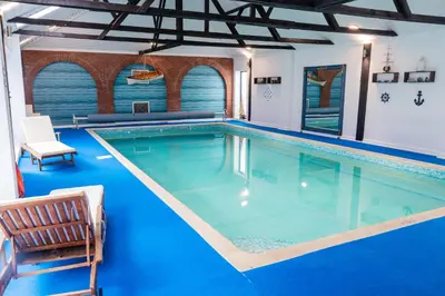 a large swimming pool in a house with blue flooring at 2 Bed Barn conversion in Tibenham